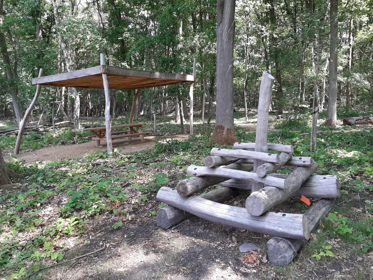 Een overdekte picknickbank en een kleine klimtoren in hout